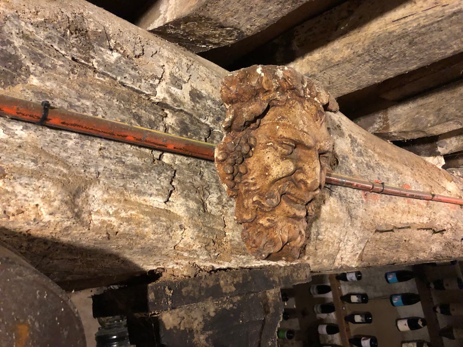 Visage sculpté dans une poutre de cave