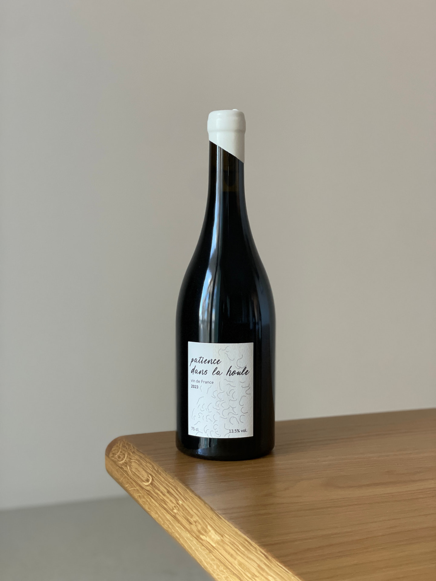 Bouteille « Patience dans la Houle », vin de France 2023, bouchon blanc, posée sur une table en bois